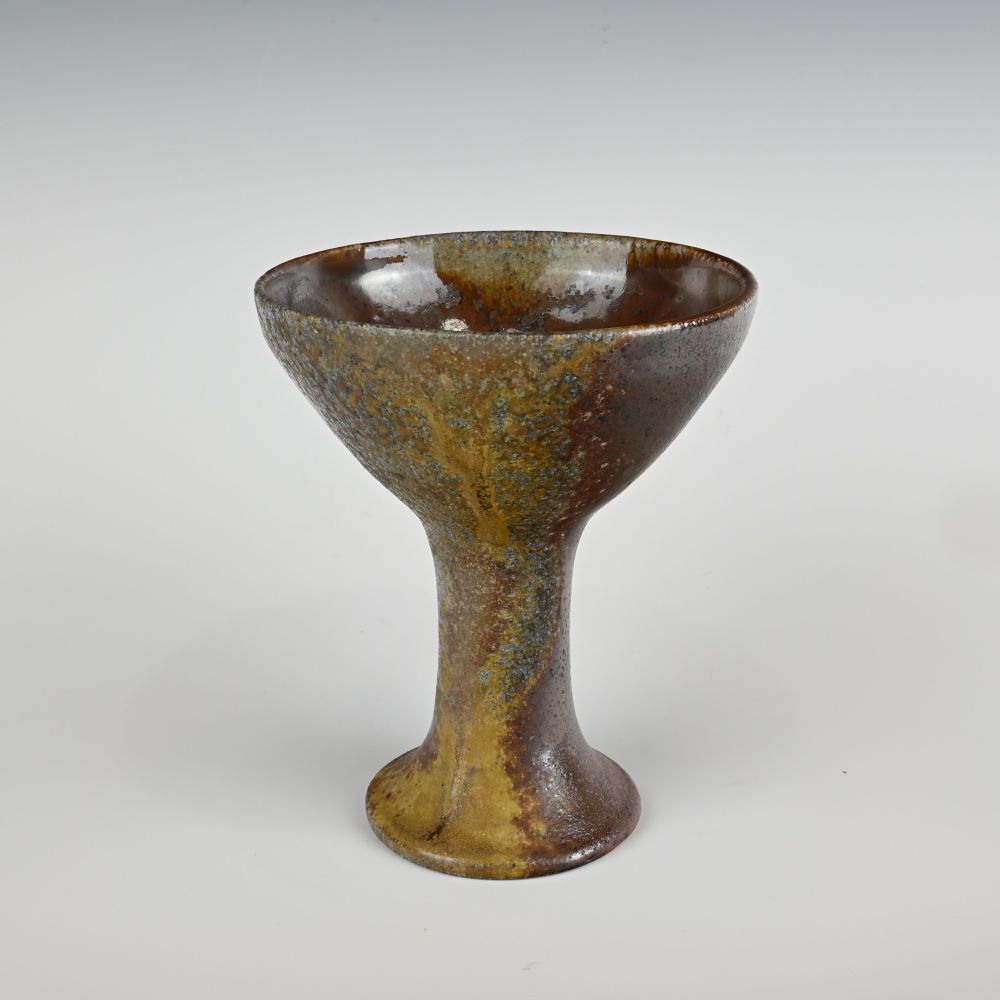 A martini-glass shaped wood fired ceramic cup, with heavy wood ash.