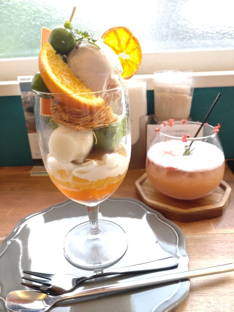 手前にそのぎ抹茶とシトラスのパフェ、奥に苺と和紅茶のモクテル。後ろには窓があり、西日が差し込んでいて逆光気味。ひとつひとつがとても美味しい！