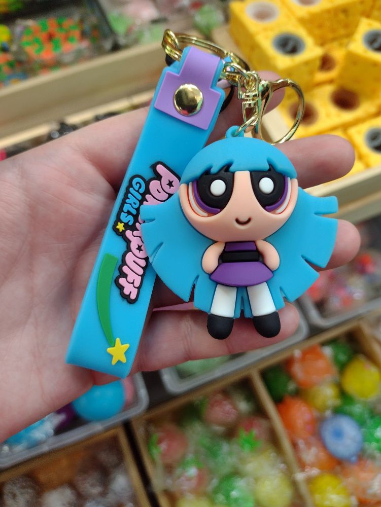 A hand holding a keychain of Bliss from The Powerpuff Girls 2016, but she is white