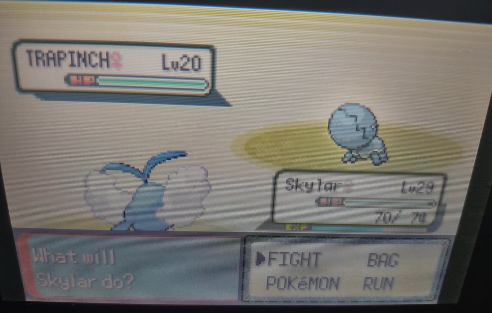 A picture of a battle in Pokémon Emerald. The scene is a sandy background. In the battle is a level 29 female Swablu named Skylar. The opposing Pokémon is a level 20 shiny Trapinch. It is a blueish green colour.