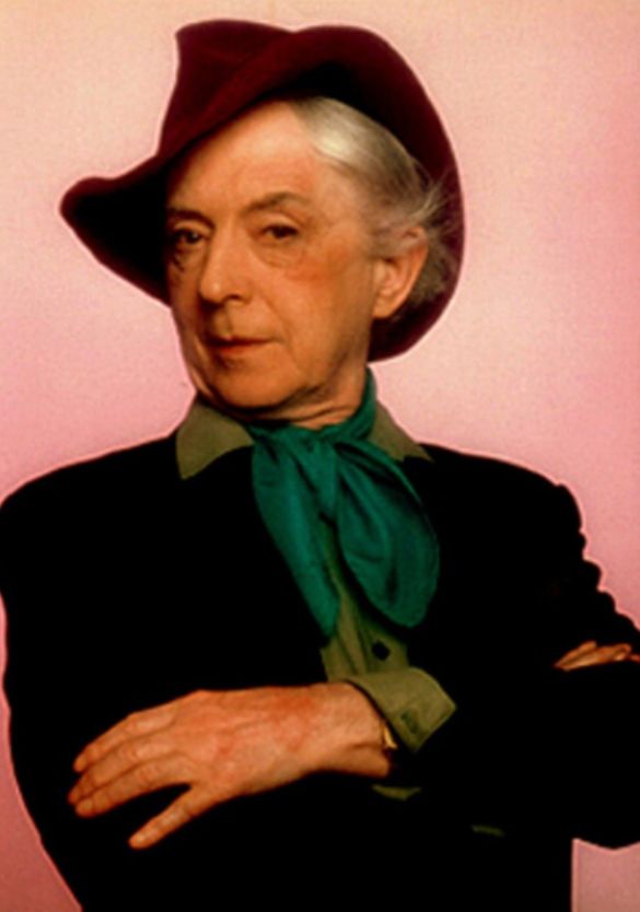 A defiant Quentin Crisp in a hat and scarf.