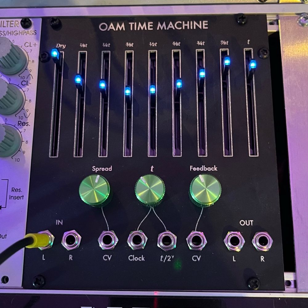 a large eurorack delay with blue LED sliders and green aluminum knobs. says OAM Time Machine at the top