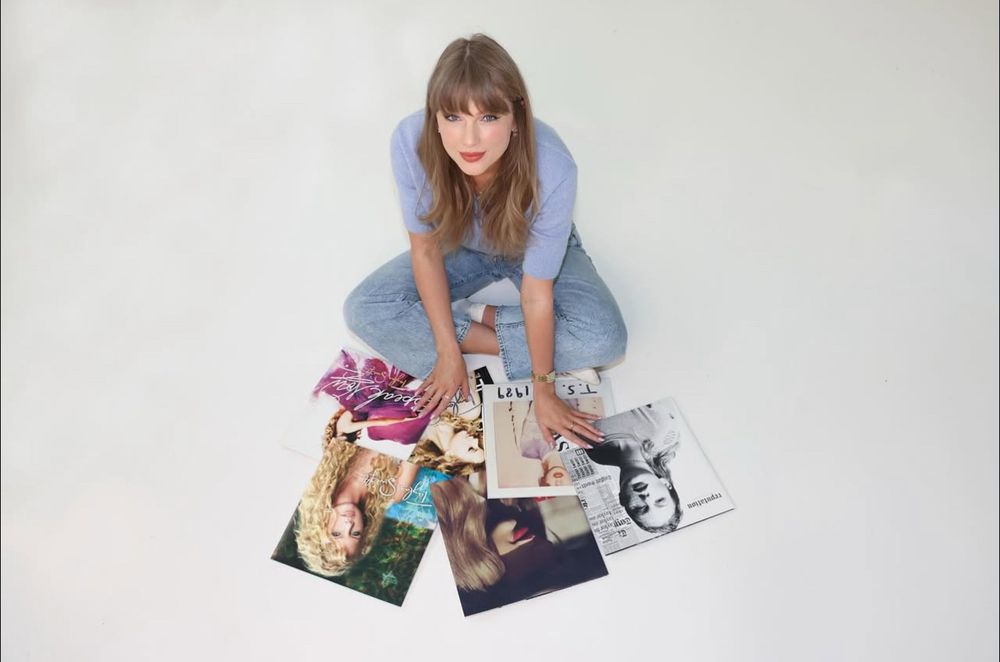 Taylor Swift sitting on the floor with her first 6 albums in front of her