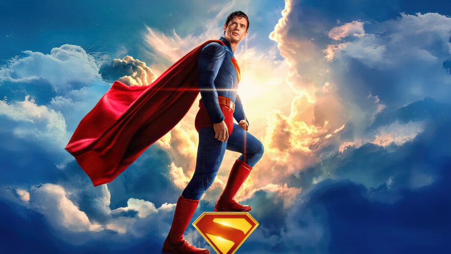 David Corenswet as Superman, standing on his own logo against a lovely sunny sky.