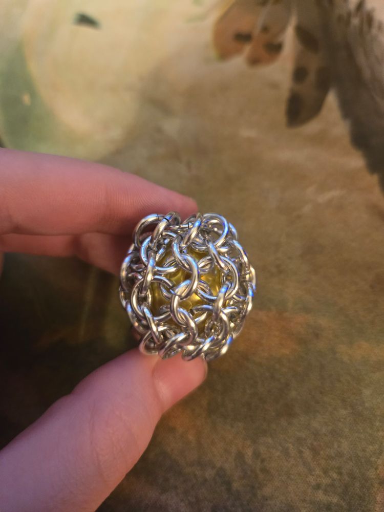 A yellow bead captured in European 4-in-1 chainmail