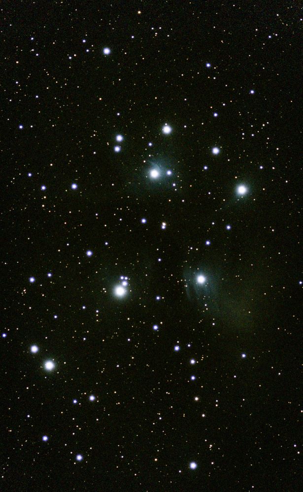 An image of the Pleiades M45 open star cluster with bright blue young stars and a little gas.