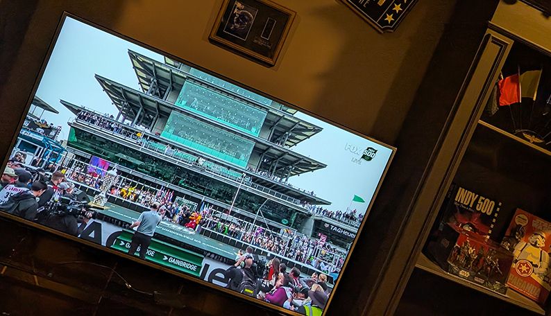 TV showing live coverage of the Indy 500, with a view of the Indianapolis Motor Speedway pagoda.