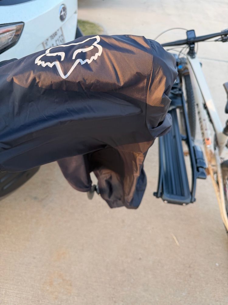 A black windbreaker jacket hanging off a hitch mounted car bicycle rack