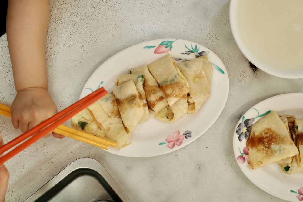 A cheese egg roll (cheese danbing) on a dish at a breakfast shop in New Taipei City