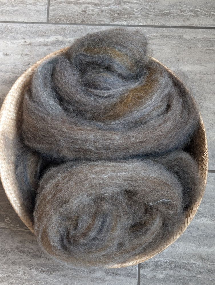 a basket of beautifully carded and dizzed blended wool, which will eventually be spun into yarn and then knit into a pair of gloves