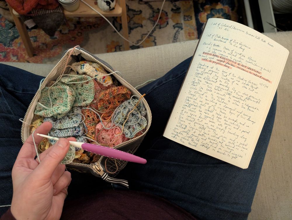 a person in blue jeans sits criss cross apple sauce on a couch. in their lap is a zip pouch of crocheted squared and a notebook with handwritten dungeons and dragons notes. a white skinned hand holds the beginning of a new square with mint green yarn and a skinny crochet hook.