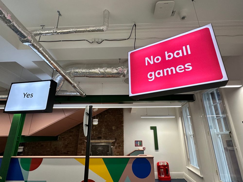 Signs suspended from the ceiling reading “no ball games” and “yes”