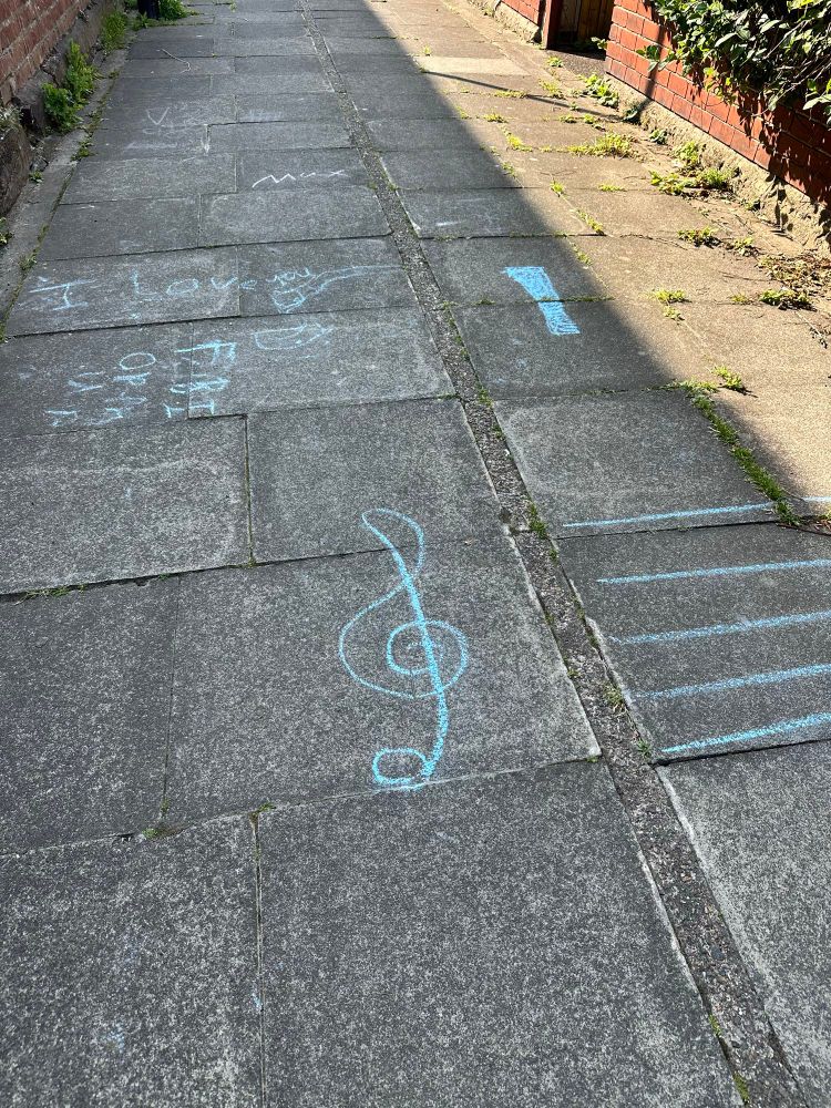 Blue chalking on a pavement, including the words “I love you” and a treble clef with staves. 