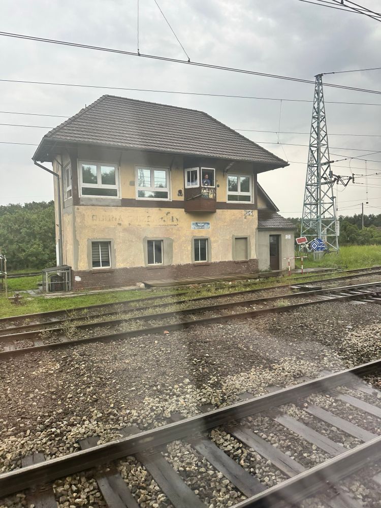 A signal box in western Poland with rails in the foreground and pylons in the distance. 