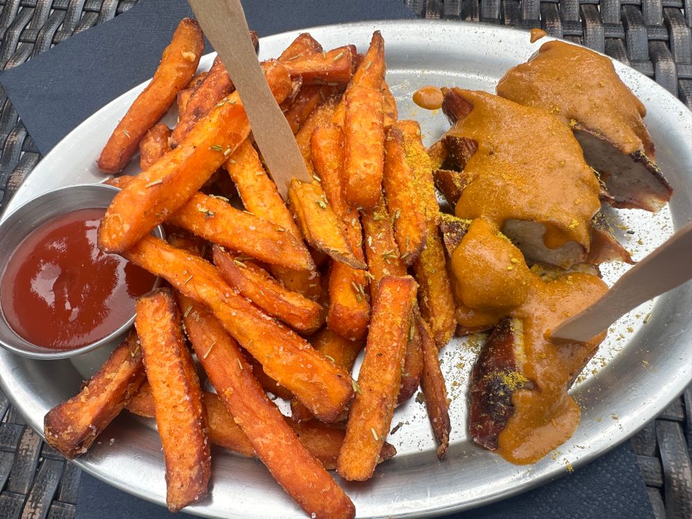 Ketchup, sweet potato fries, curryworst on a metal plate