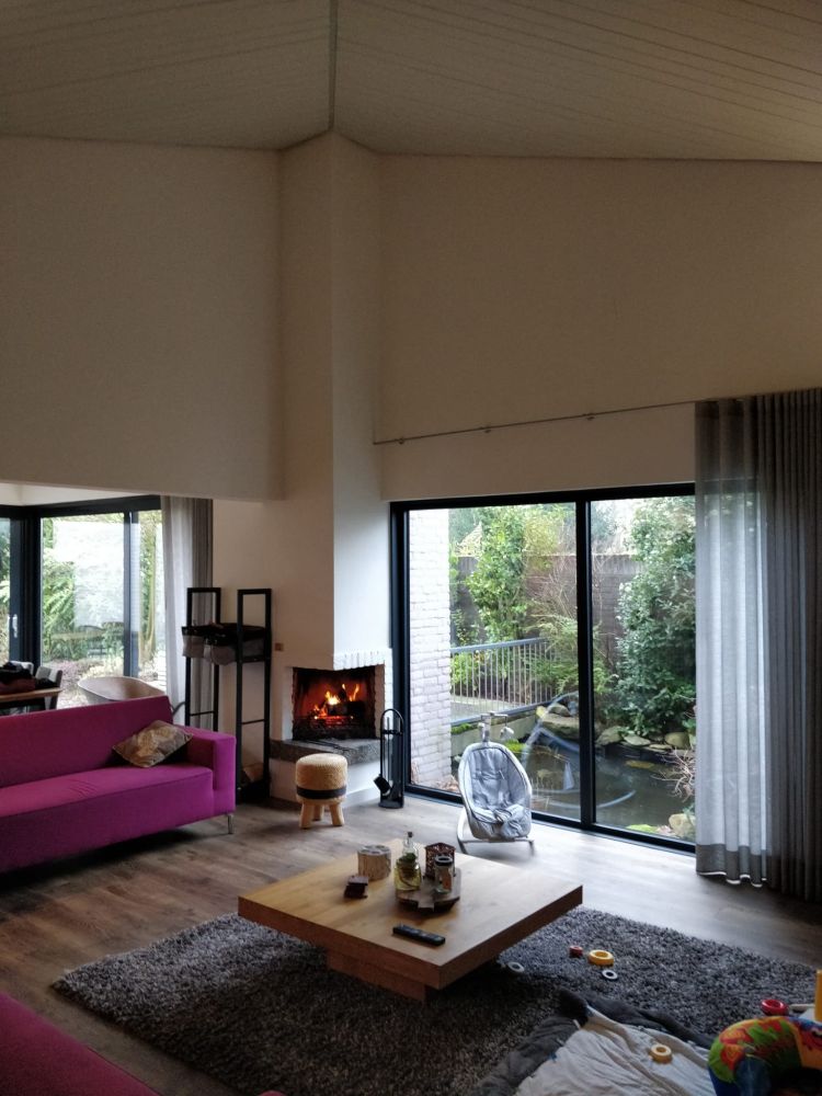 Chimney without wooden panels. There is a fire burning, a pick couch and a little pond outside.