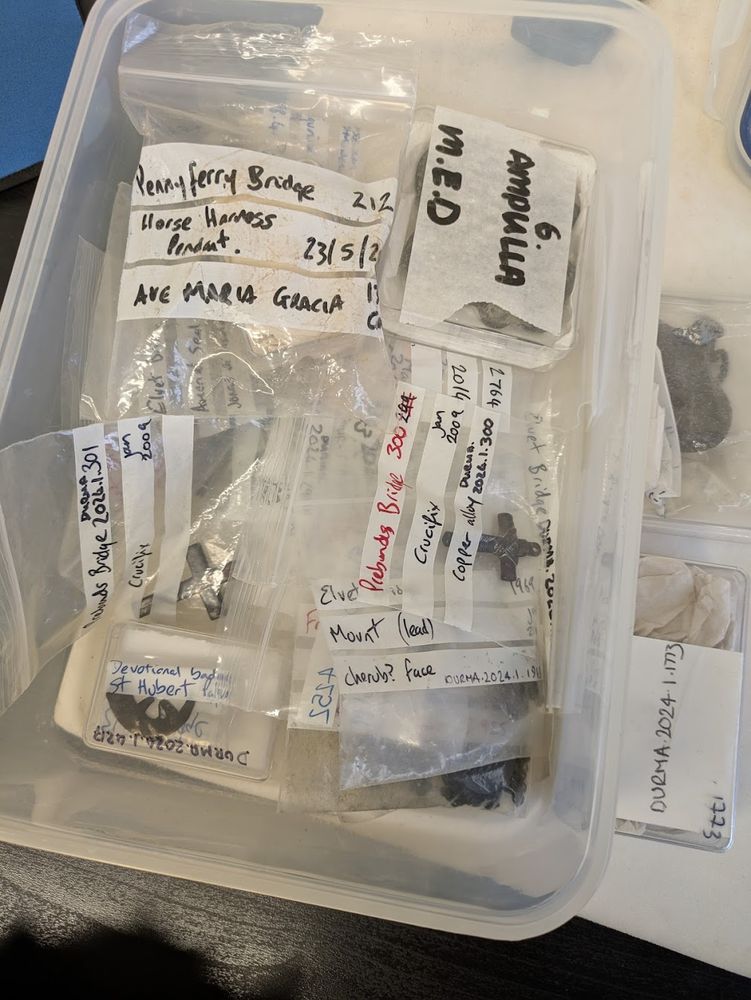 Plastic bags with objects inside. Some have writing visible like Ave Maria Gracia, Ampulla and crucifix.
