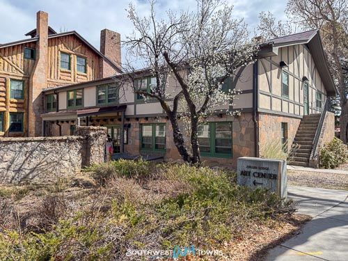 View of Tudor-style building with flowering tree in front and a sign that reads Fuller Lodge Art Center.