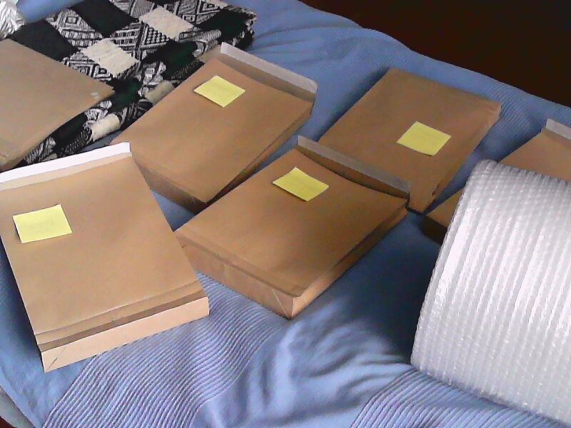 A low-resolution photo of five packages laying on my bed alongside a giant roll of bubble foil.