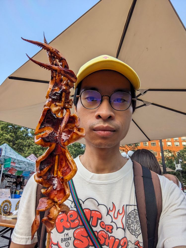 selfie of me with a giant skewer of grilled squid