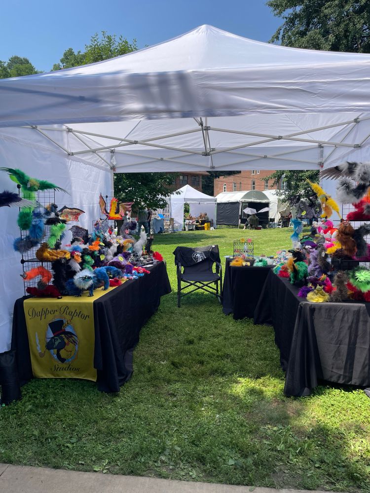 Booth set up in outdoor setting - art dolls spread around tables under a white tent