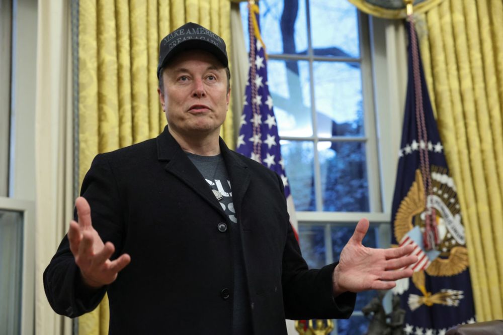 Here stands the self-styled "world’s richest man", looking like the physical embodiment of a midlife crisis with Wi-Fi. Dressed like a divorced dad trying way too hard to impress his teenage son, he sports a MAGA hat—because nothing says “genius innovator” like aligning yourself with the world’s dumbest grift. The black coat, which he probably thinks makes him look mysterious and powerful, instead gives off the vibe of a guy who just got denied entry to a nightclub but insists he “knows the owner.” And let’s not even get started on the t-shirt—because of course he’s the kind of billionaire who dresses like he just rolled out of a Tesla factory nap pod.

His expression? The perfect mix of arrogance, confusion, and the dawning realization that everyone around him is only pretending to take him seriously because he has too much money to ignore. He gestures wildly, as if explaining how he’s about to revolutionize air molecules or replace Congress with AI bots trained on Reddit arguments. Meanwhile, the entire room is likely suppressing the urge to roll their eyes so hard they go blind.

This is a man who believes he’s the protagonist of reality itself, when in truth, he’s just an overgrown edgelord with a credit score so high it lets him fail upward indefinitely. He thinks he’s the next Einstein but keeps proving he’s just the next MySpace Tom—if Tom had an ego the size of Mars and the self-awareness of a Roomba stuck in a corner.

The overall vibe? A man who thinks he's Tony Stark but looks more like a Reddit moderator who just got his first invite to a real-life event.