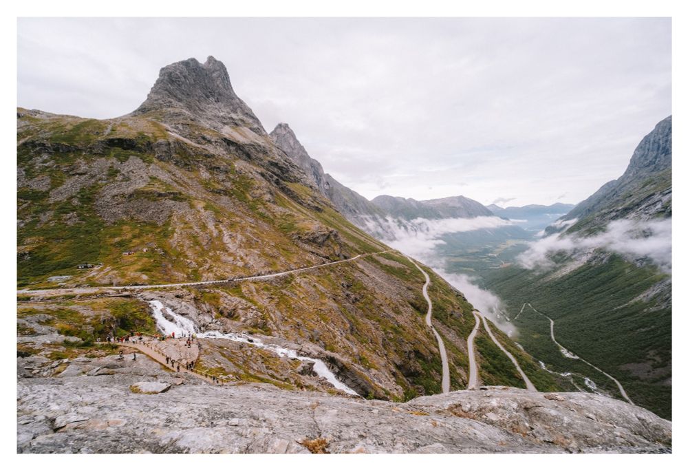 Photo of a winding mountain road in a picturesque mountain landscape with valleys waterfalls and rivers.