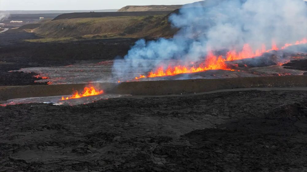 aerial photo of the new iceland eruption. orange lava spewing out of a long fissure in the ground, by RÚV / Ragnar Visage