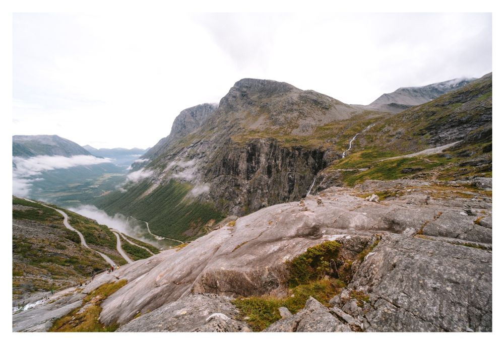 Photo of a winding mountain road in a picturesque mountain landscape with valleys waterfalls and rivers.