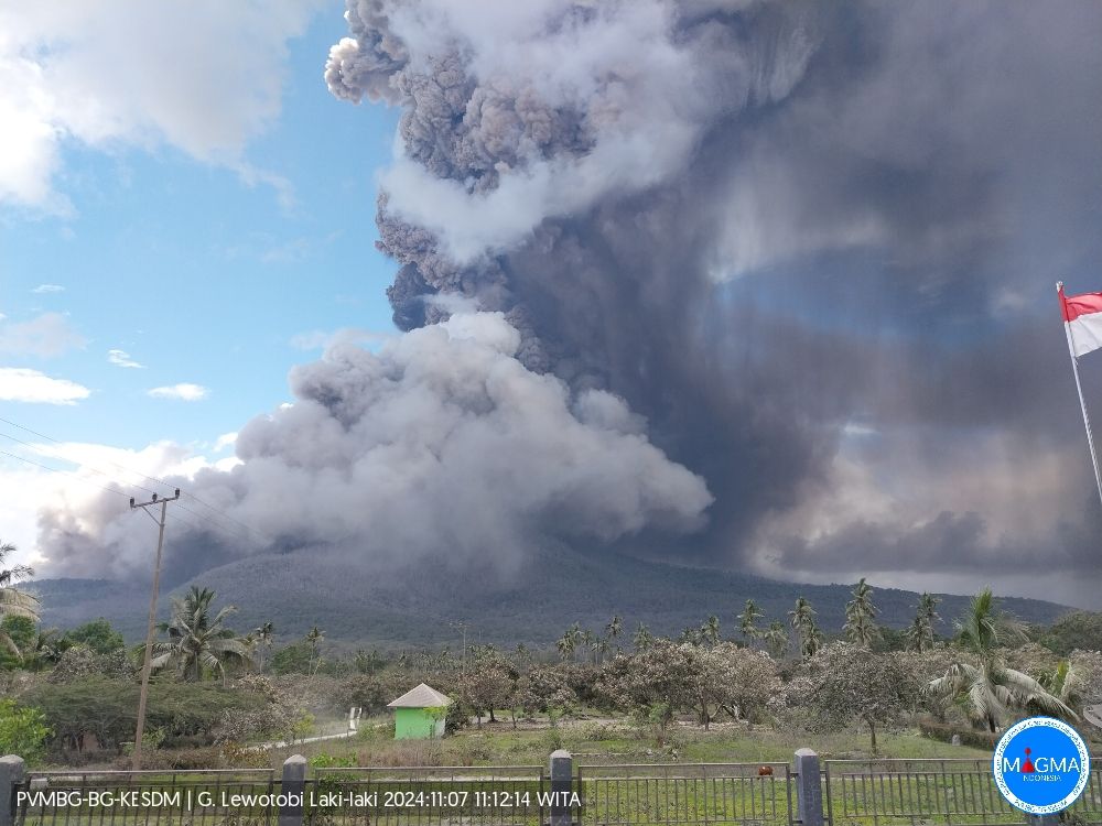 Photo of Lewotobi volcano at day. Volcano is not visible because of a dense light gray to gray ash cloud rising into the sky.