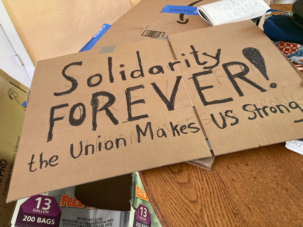 Cardboard sign: Solidarity FOREVER! The Union Makes US Strong