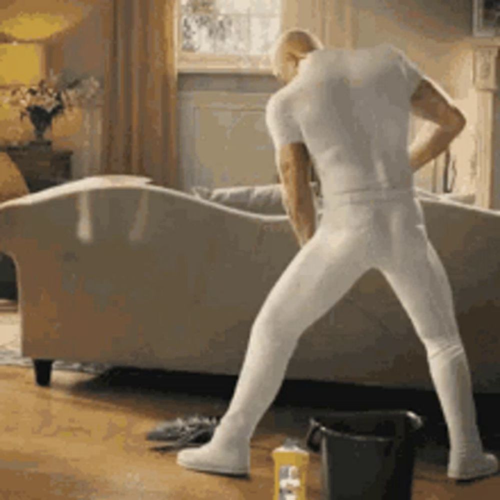 a man in white underwear is standing on one leg in a living room .