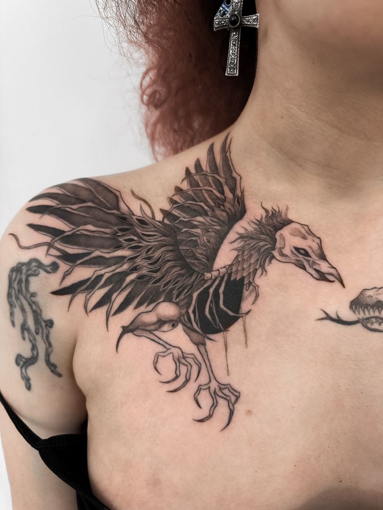 Phoenix tattooed on chest/collarbone area, in a blackwork horror illustrative style. Right collarbone 