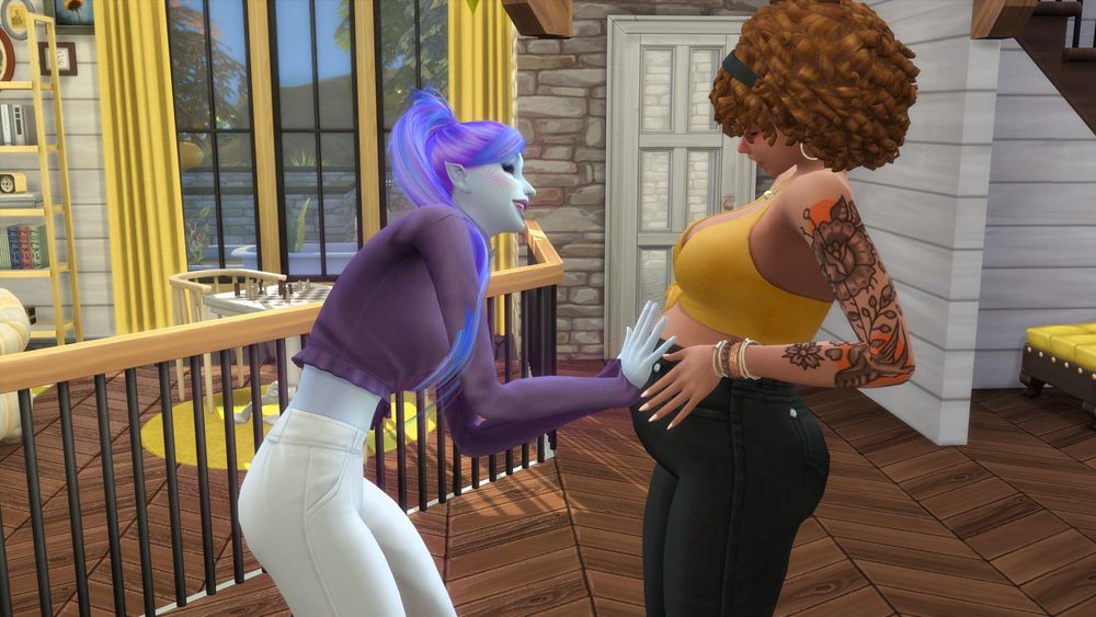 Two sims inside of a room with wooden and stone walls. One sim has her hands on the other sims pregnant belly with an expression of joy on her face.