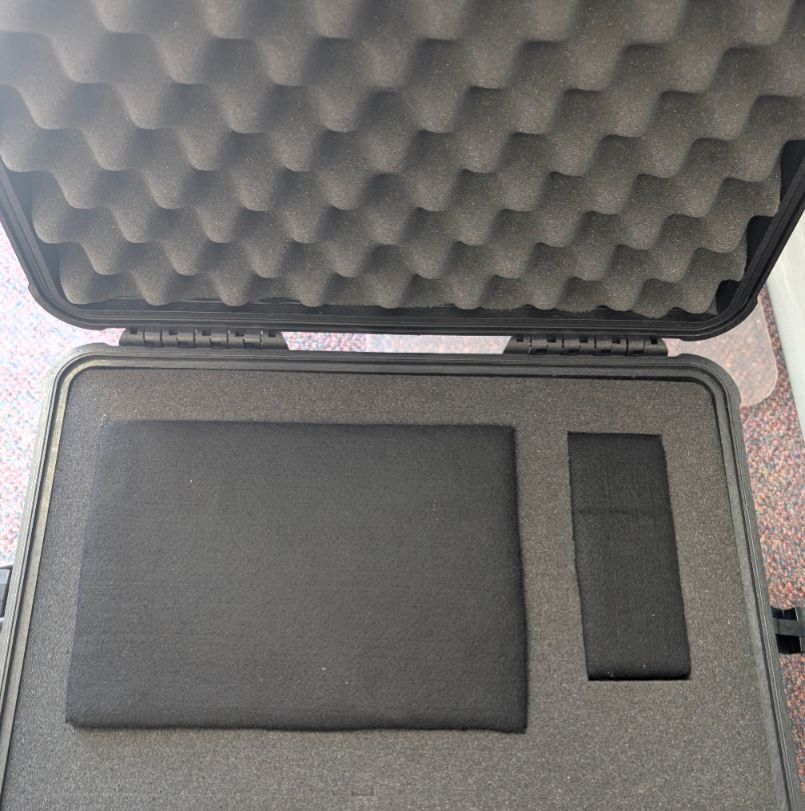 A ridiculous heavy duty case with foam on the inside and two dark cushions are in. They are adding even more protection to a dvd player that is not visible. Part of a library of things for rent at my local library. It's like a bomb proof case, VIP treatment for this dvd player. 