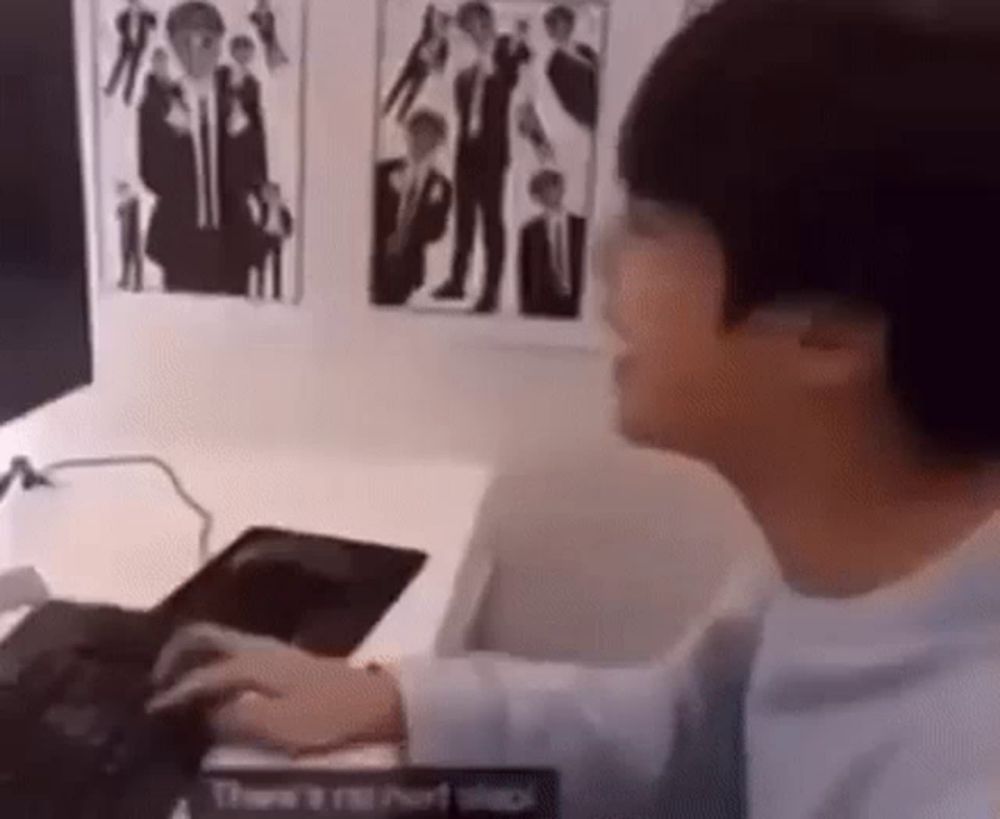 a young man is sitting at a desk typing on a keyboard .