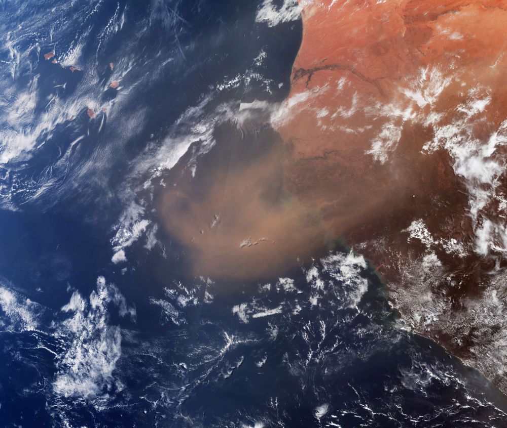 The Sentinel-3 optical image shows a dense, orange plume of Saharan sand over approximately 150 000 sq km of the eastern Atlantic Ocean. The small islands of Cabo Verde peek out from beneath the clouds in the top left corner.
