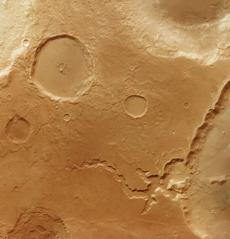 Part of the feature-rich Deuteronilus Cavus depression on Mars. Evidence of glacial activity is apparent around much of the inner crater walls as rock-covered ice has flowed downslope. At the bottom a channel with several branches breaches the crater wall; it likely once contained flowing water.