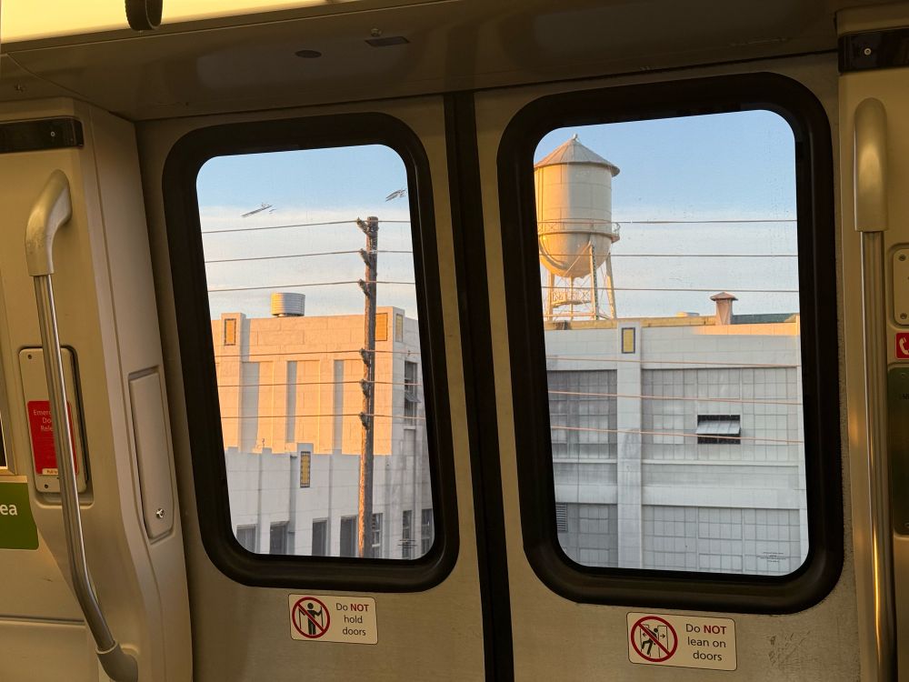Water tower and building through the windows of a BART train