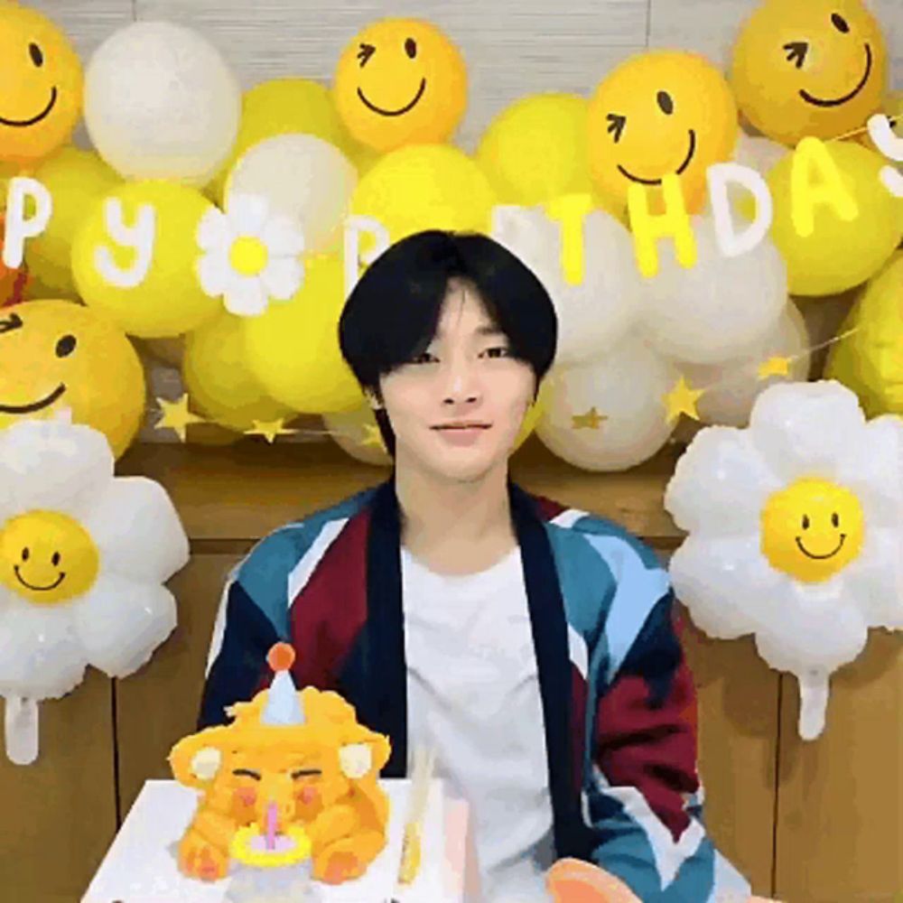 a man is sitting in front of a birthday cake with balloons that say happy birthday