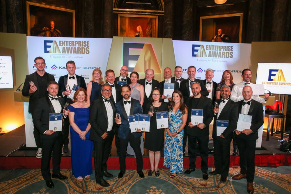A group of smartly dressed people standing on a stage with trophies & certificates - they are all winners, finalists or judges at the 2025 Enterprise Awards.