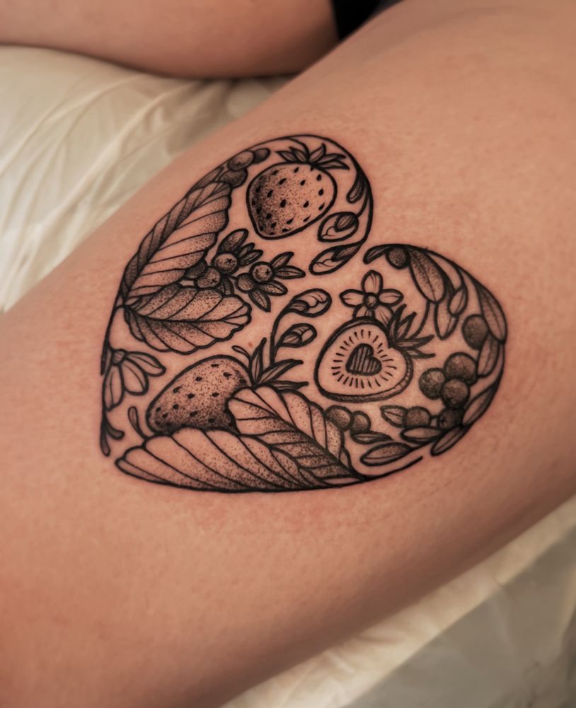 This is a photo of a tattoo on a woman’s thigh. The tattoo is of strawberries and cranberries curving into the shape of a heart. This tattoo is done in black line work style with stipple shading. Done by Molly Vee in Seattle WA. 