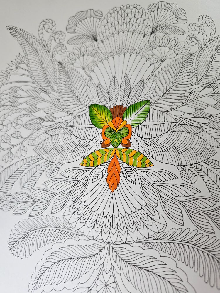 A coloring page full of leaves and ferns with the center colored in yellows, oranges, and greens. From the book "Tropical World: A Coloring Book Adventure" by Millie Marotta, page 1.