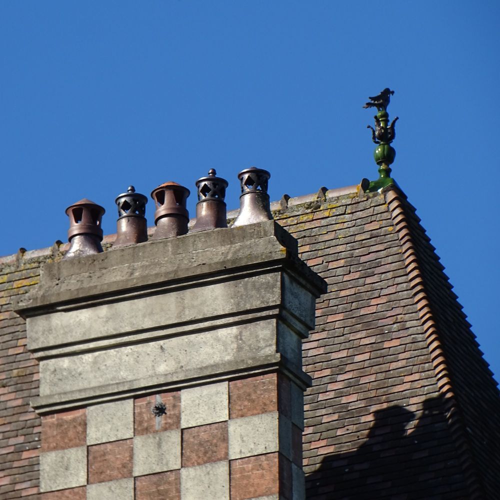 An ornate chimney stack in sunlight with pepper-pot-like chimney pots on the top.