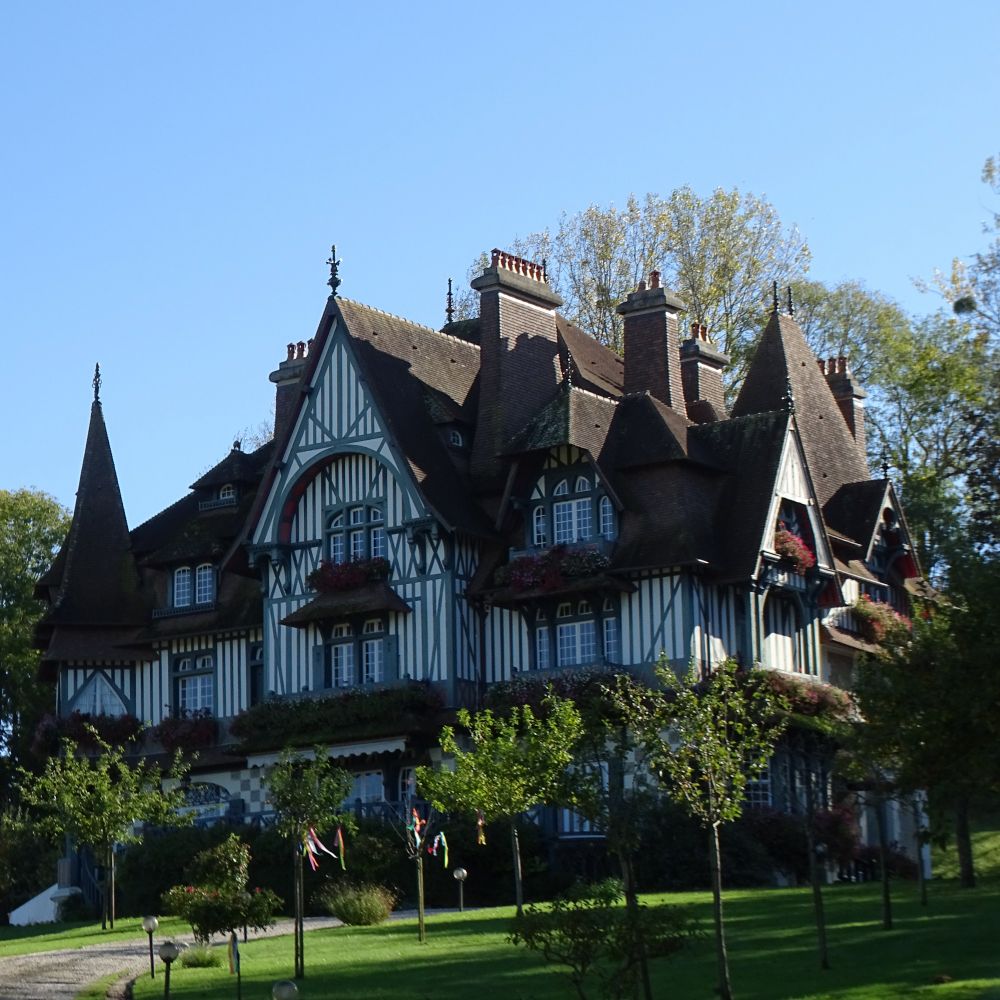 An enormous and elaborate timber-beamed house with many chimneys set in parkland.