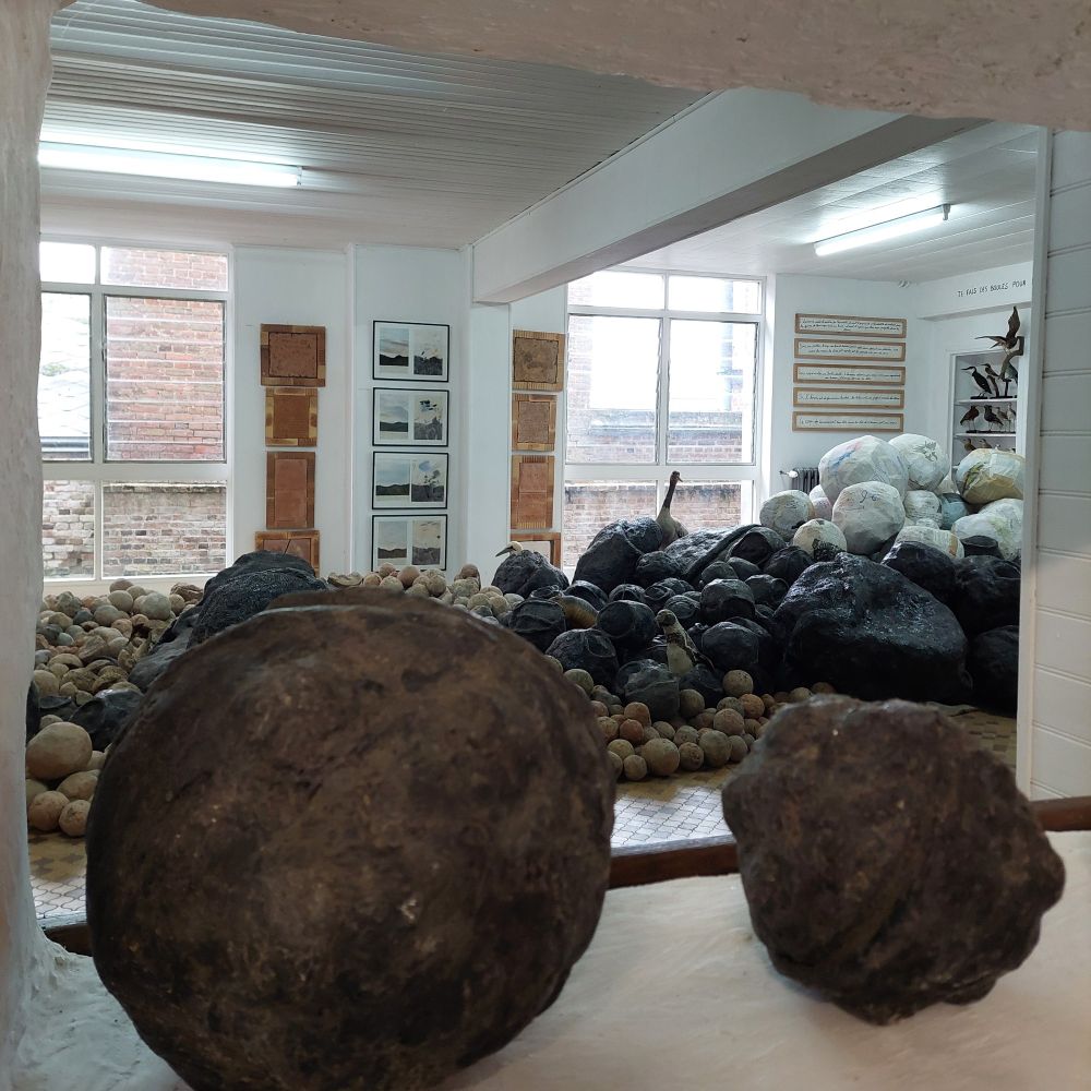 Vue à l'intérieur d'un petit musée avec des œuvres composées de boules de différentes tailles et couleurs, et faites de différentes matières 