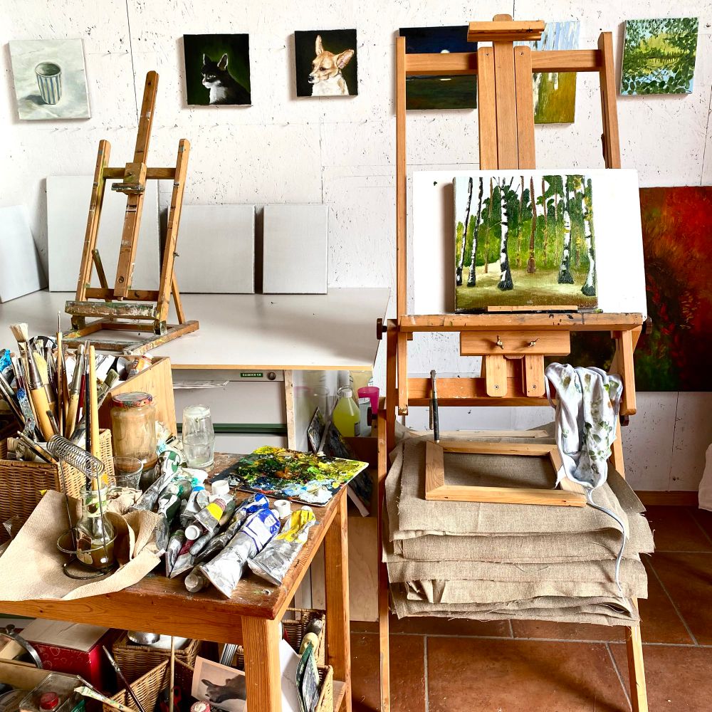 Atelierwand mit Bildern und Staffelei davor