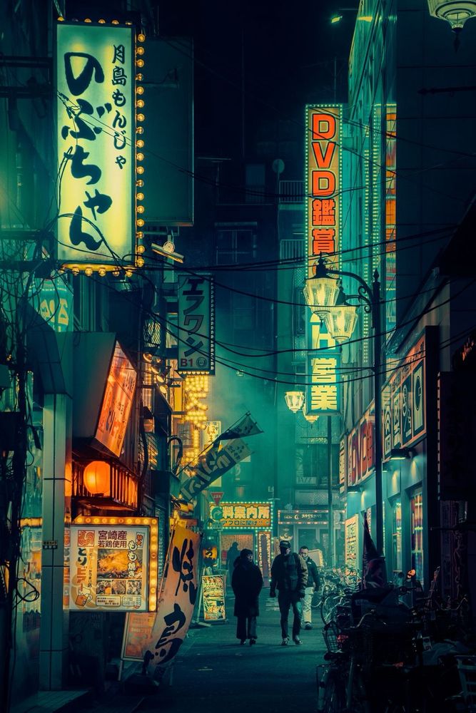 Photography by Liam Wong of Tokyo at night. Several silhouettes pass through an alleyway in Shinjuku. The colors are green, orange and yellow.