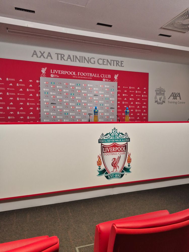 The stage at the AXA Training Centre in Kirkby- a white banner with the Liverpool crest in the centre. Above are two advertisement boards - a smaller grey one for the FA bordered by a larger red on for Liverpool 