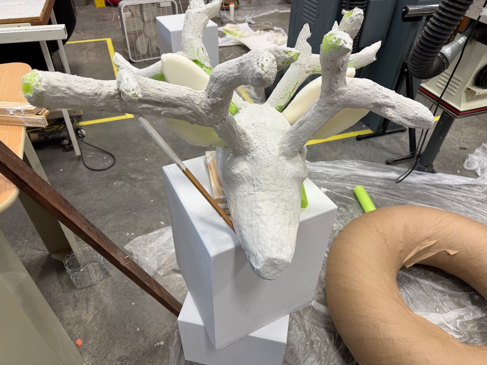 Front view of the head being covered with papier-mâché clay
The antlers are being annoying so I had to prop them up to dry correctly
